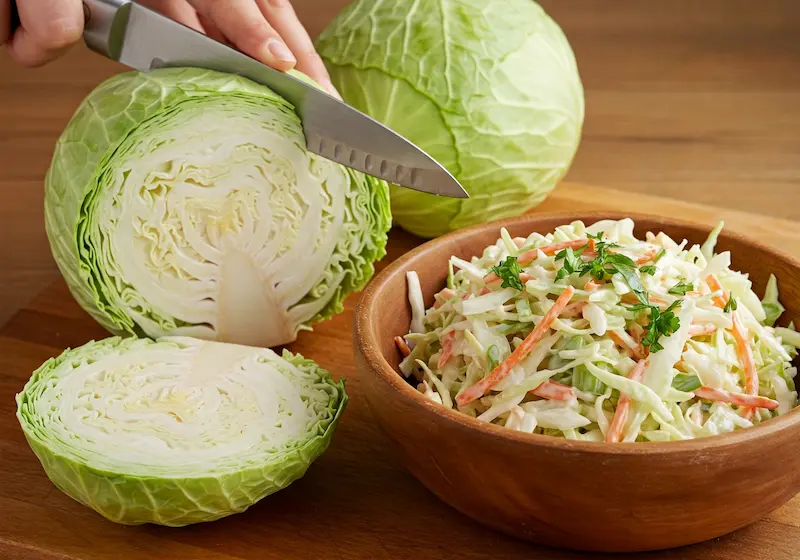 A large white cabbage being sliced in half