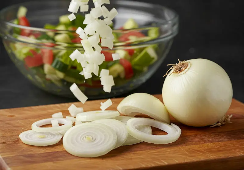 Sliced white onions arranged in concentric circles on a cutting board